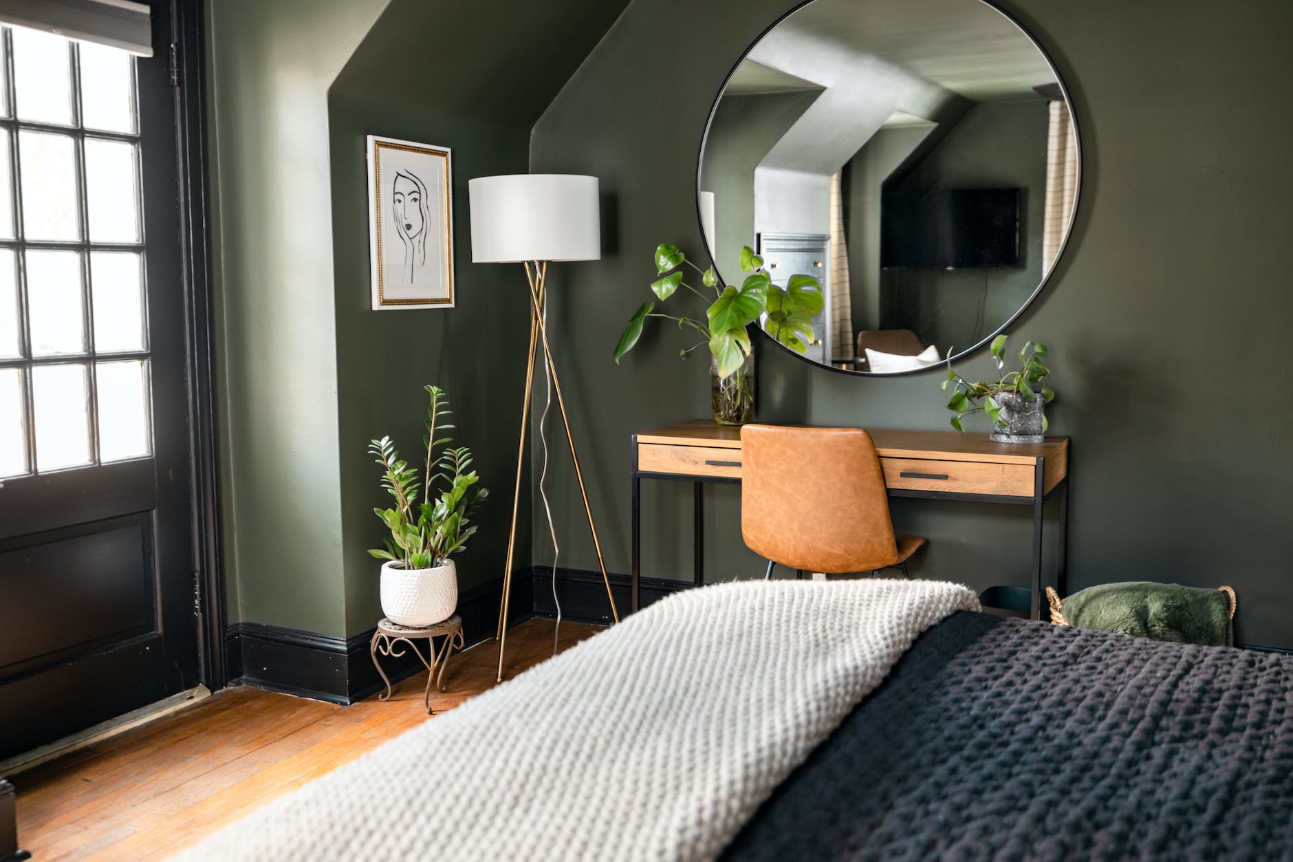 a wooden table with green plants near the mirror